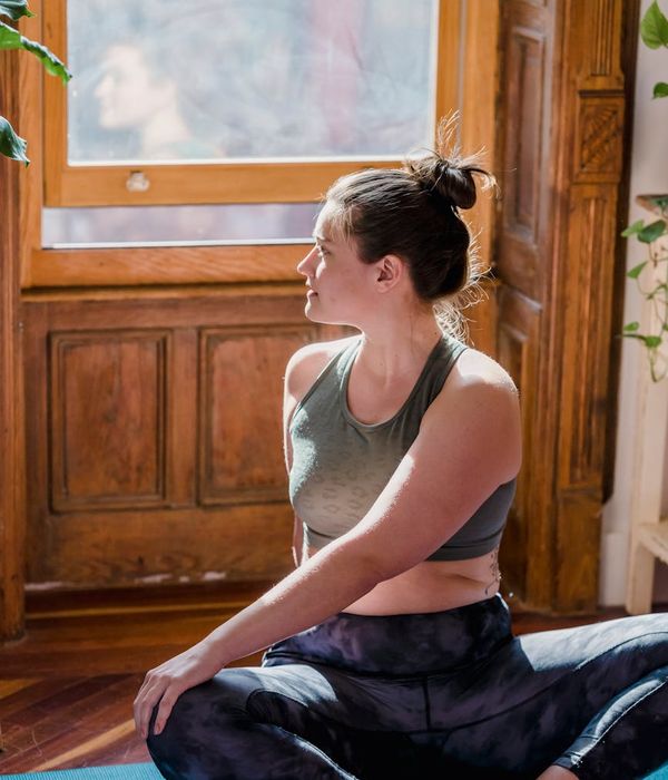 A woman stretching peacefully in a bright, sunlit room.